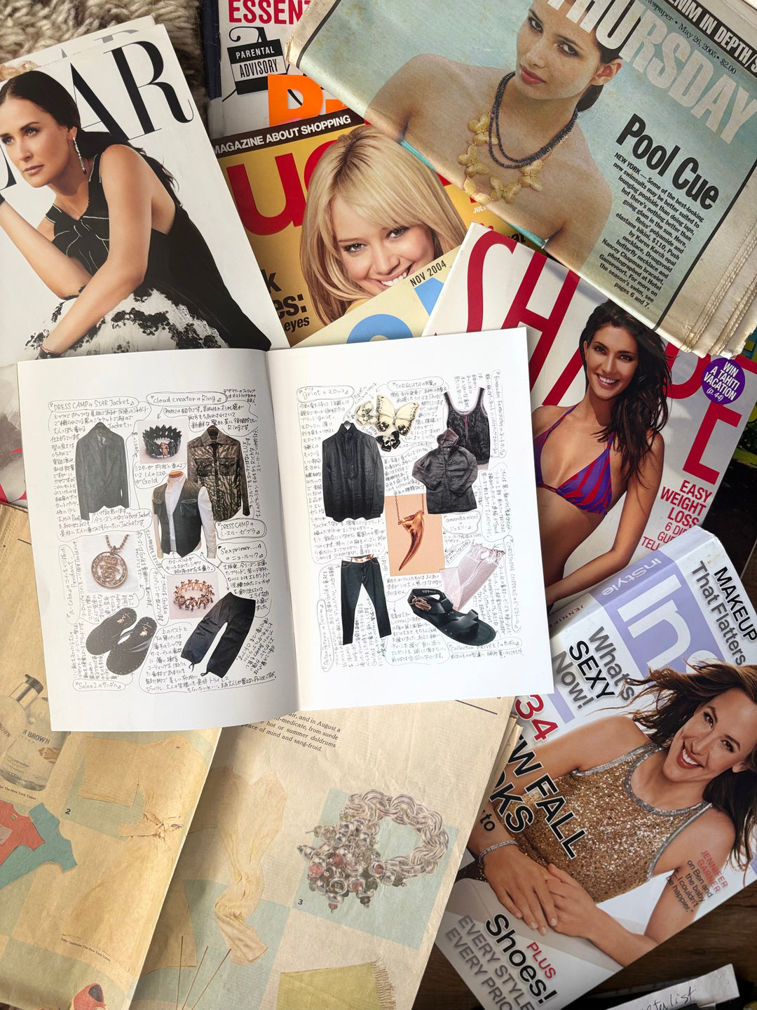 Open fashion magazines surrounding an Amanda Nicol jewelry catalogue,  studio sketchbook and collectible jewelry design references.