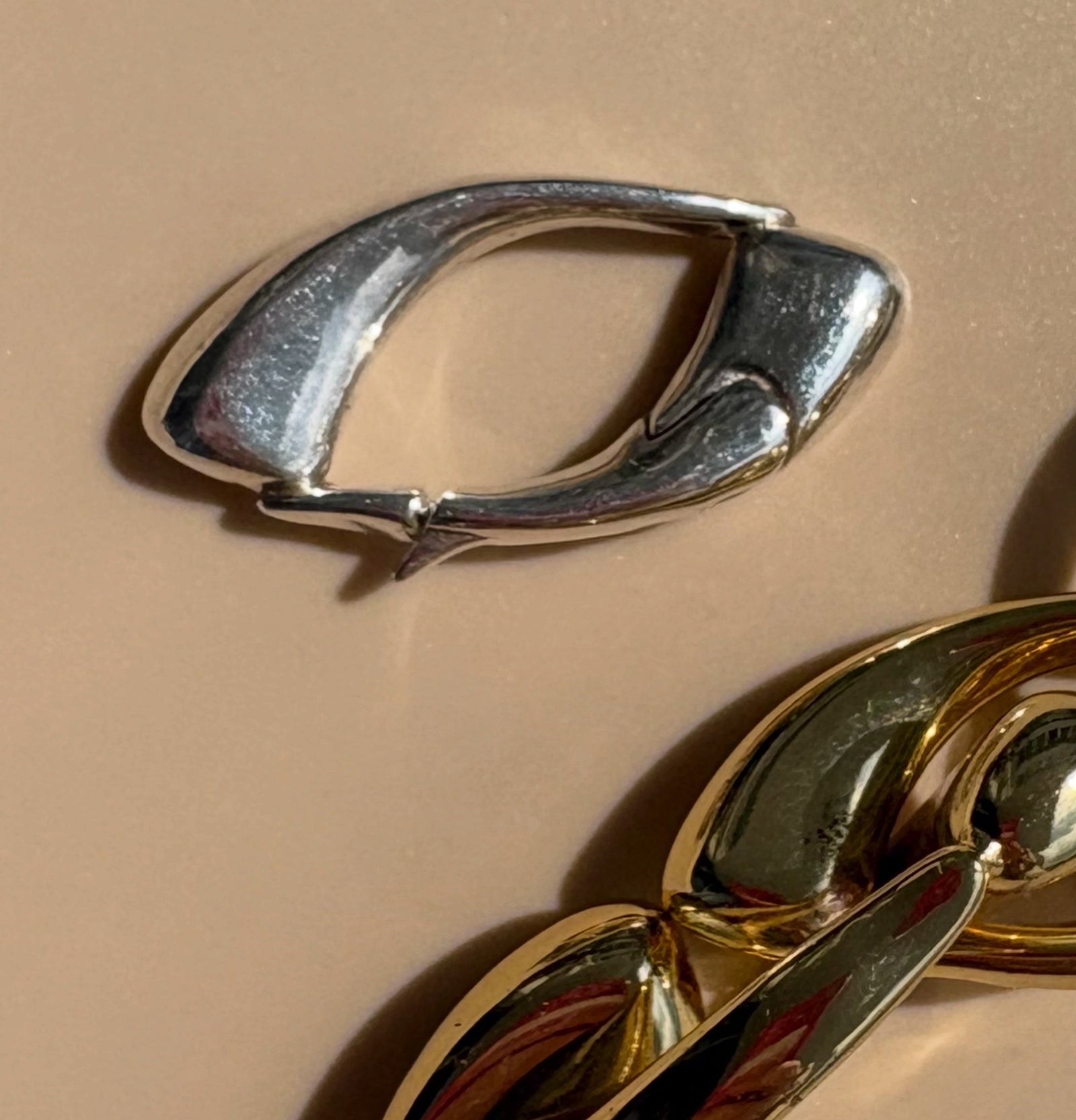 Close-up of the signature Culebra Closure in cast bronze sterling silver beside antique bronze Culebra bracelet links