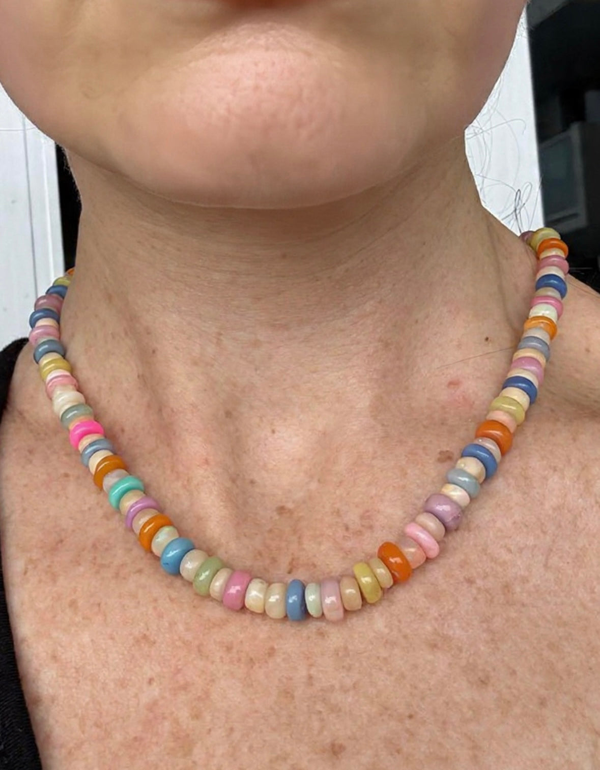 Hand-strung opal rondelle bead necklace worn by a person