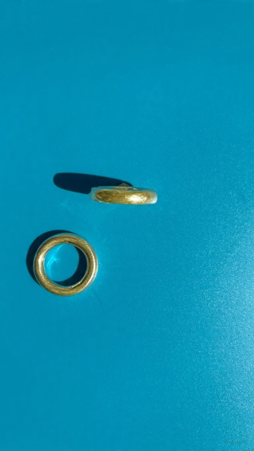 Minimalist 18 carat gold band ring with rounded sculptural form shown in side profile on blue background