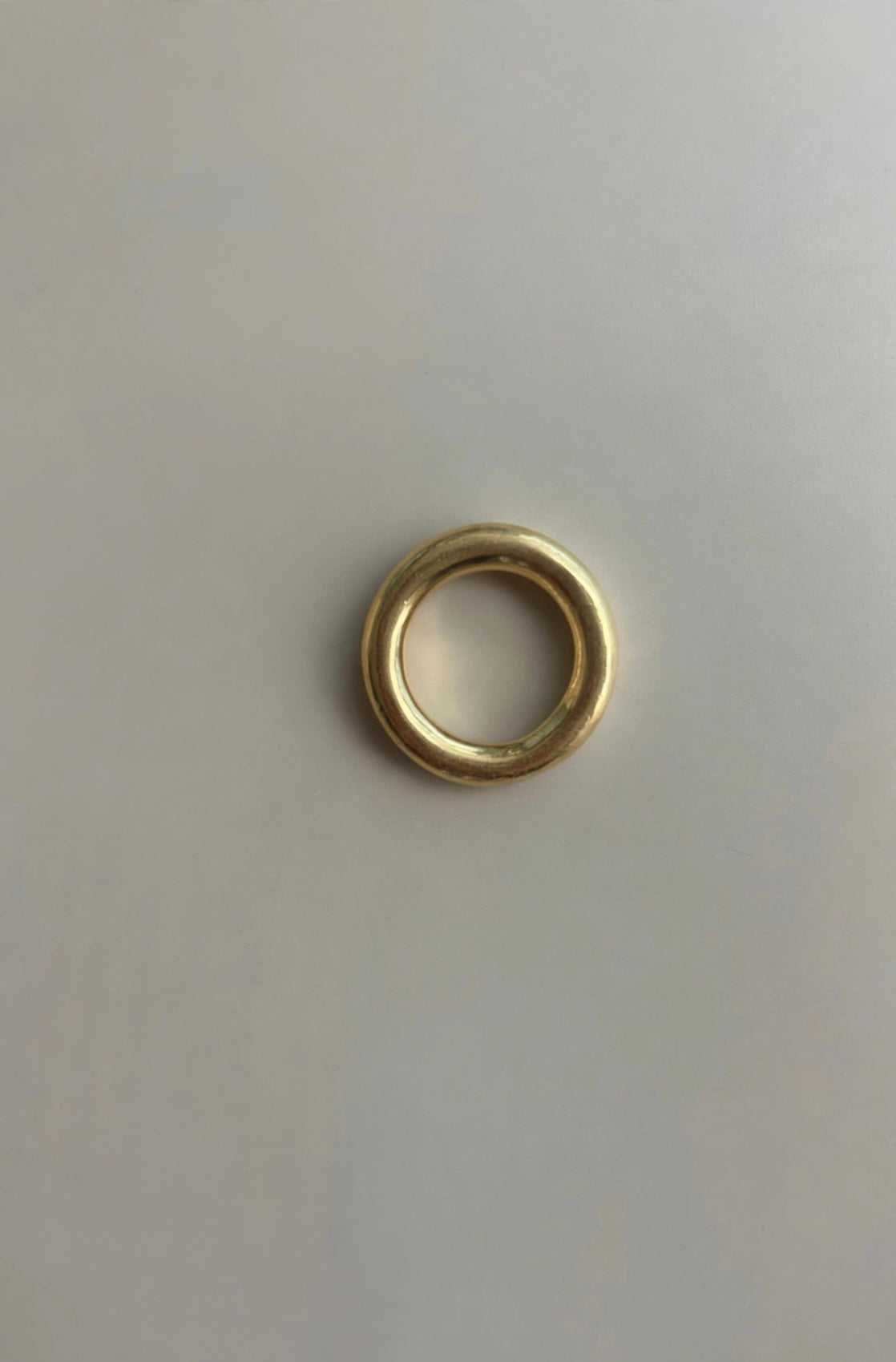 Ring One, a hand-carved rounded band in solid 18K gold, photographed from above on a light background.