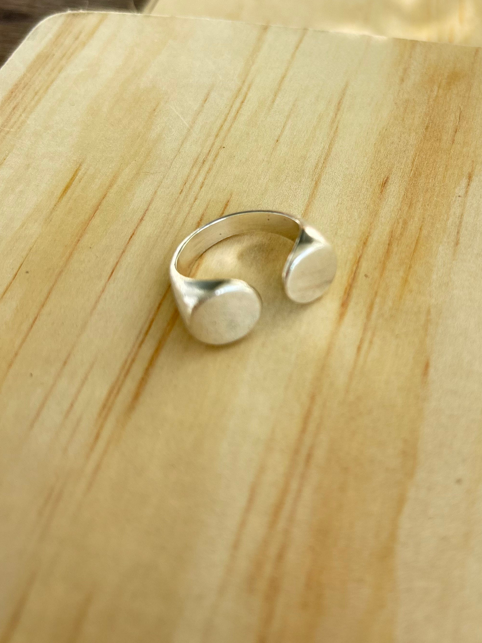 Dot Ring in 925 sterling silver by Jewelry One of a KIND, featuring two rounded sculptural ends and an open band, photographed on natural wood.