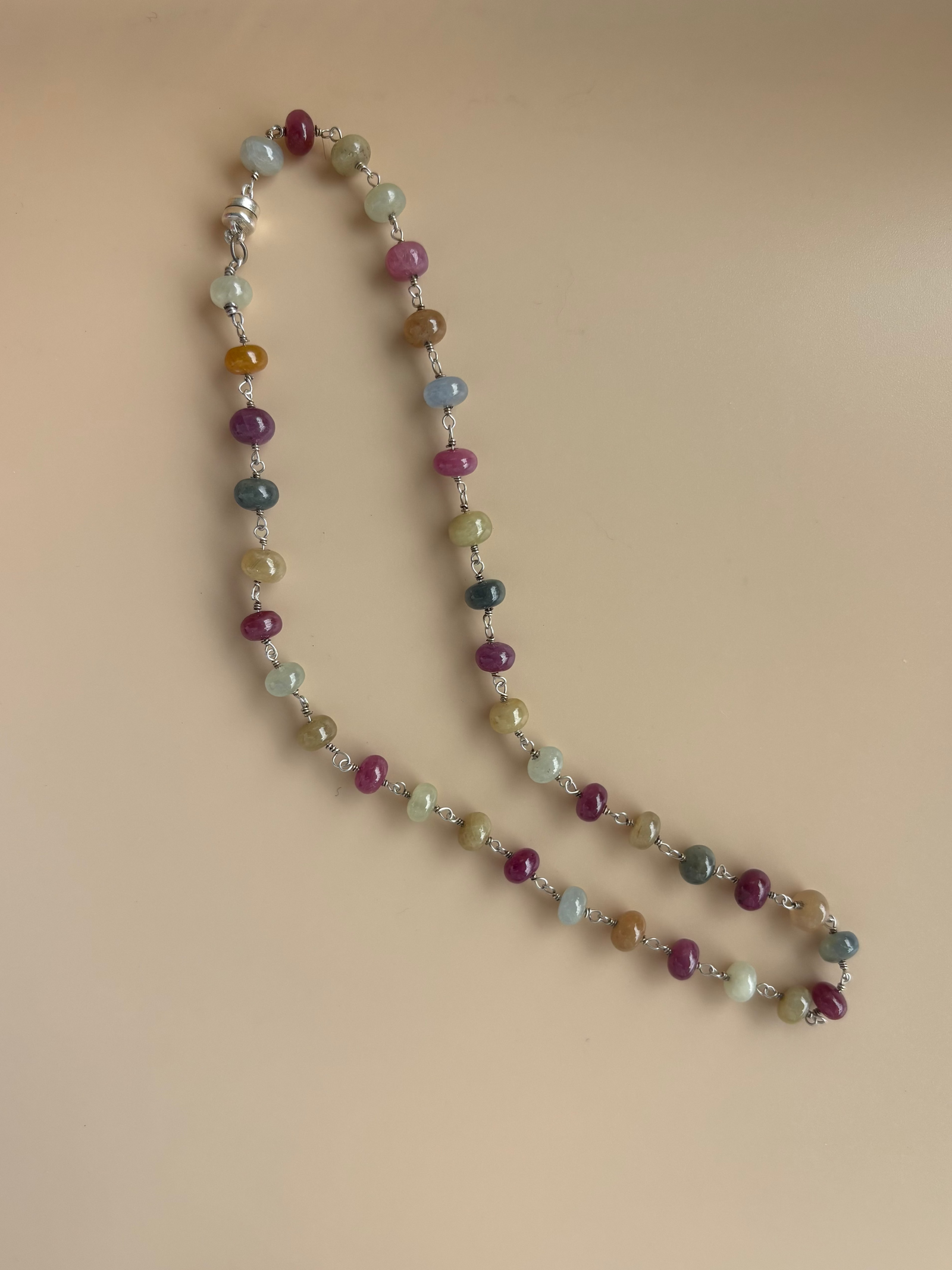 Mixed sapphire rondelle strand necklace with multicolor natural stones on neutral background