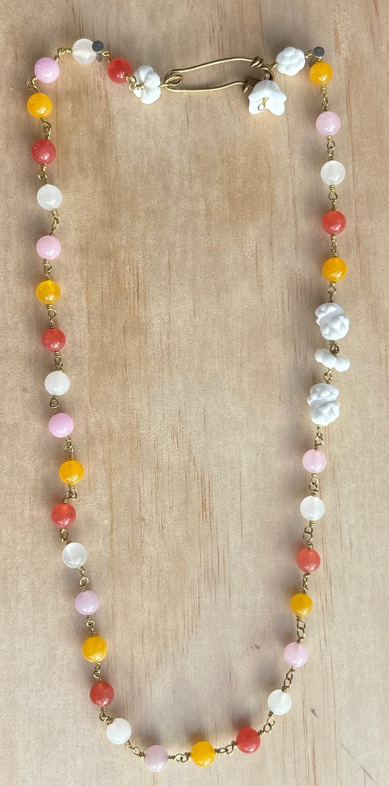 Rainbow quartz and porcelain necklace shown on blue background. Survivor-made ethical jewelry representing remembrance.