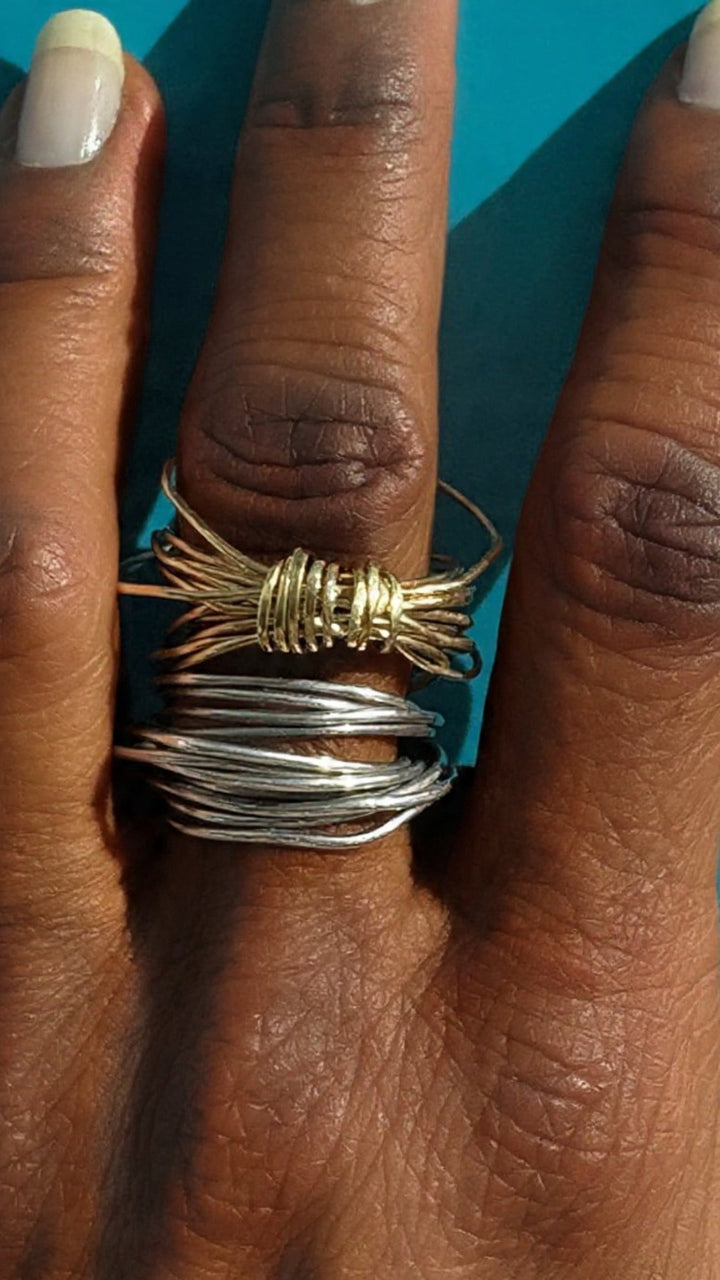 Close-up of a hand wearing two wire-rings fingers against a blue background