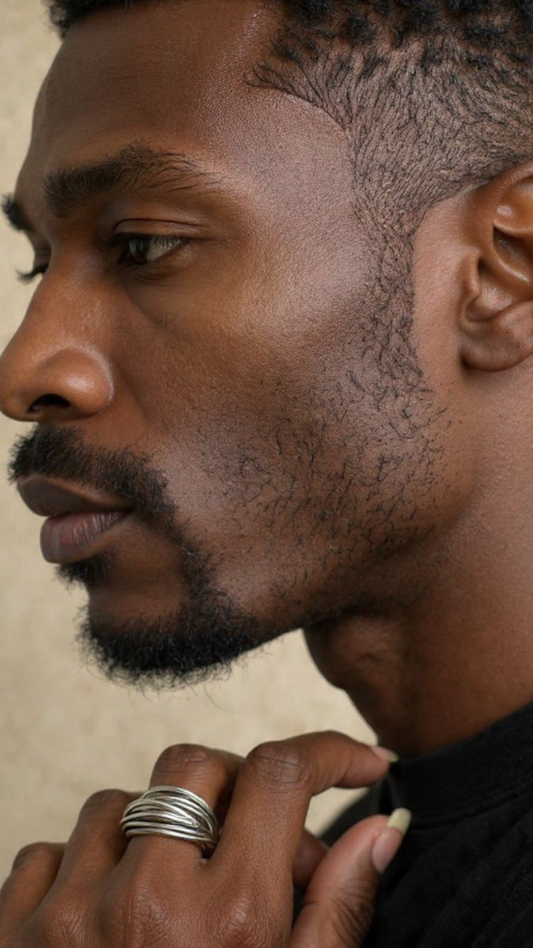 Close-up of a man with a beard wearing a wire ring on his hand against a neutral background.Ethical luxury jewelry by Jewelry One of a KIND, symbolizing unbroken strength and resilience.