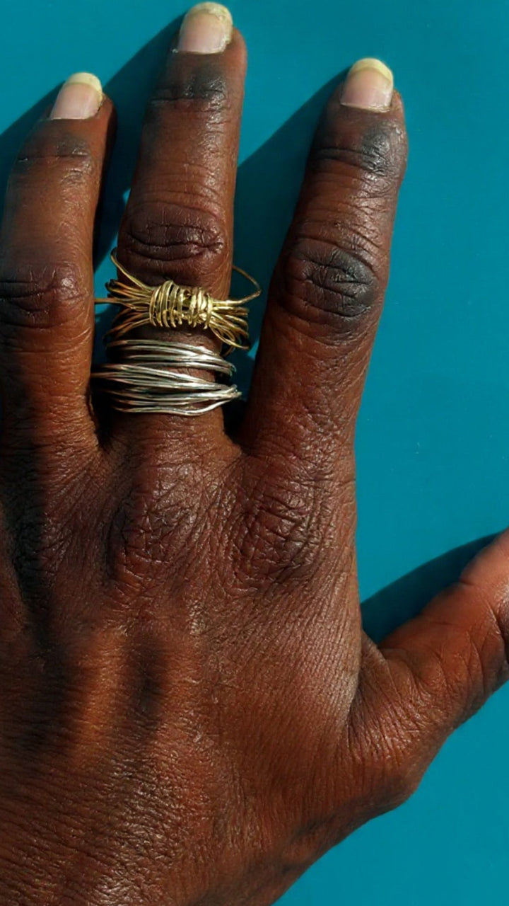 Hand with gold and silver wire rings on a blue background 