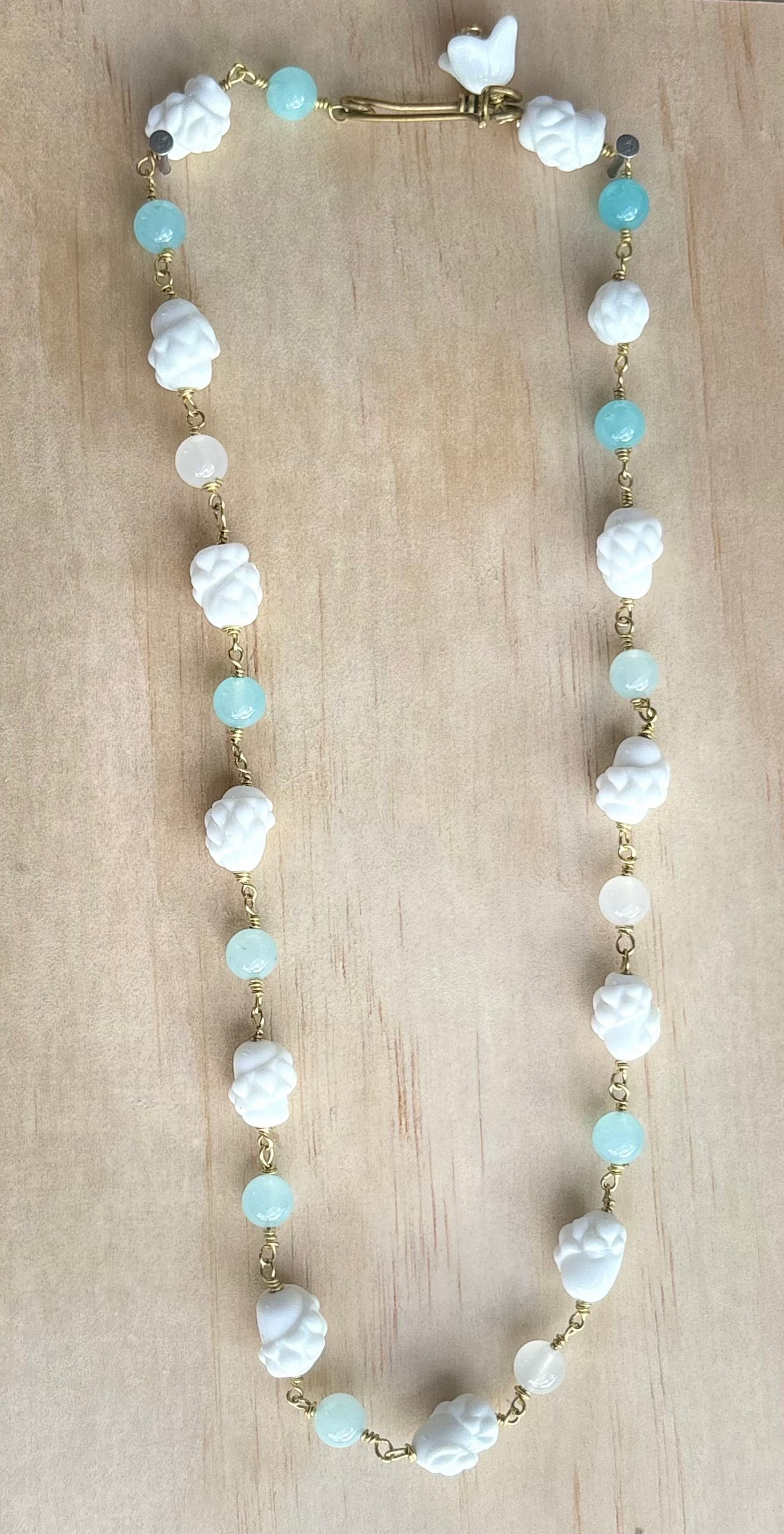Baby blue quartz necklace displayed on beige surface. 