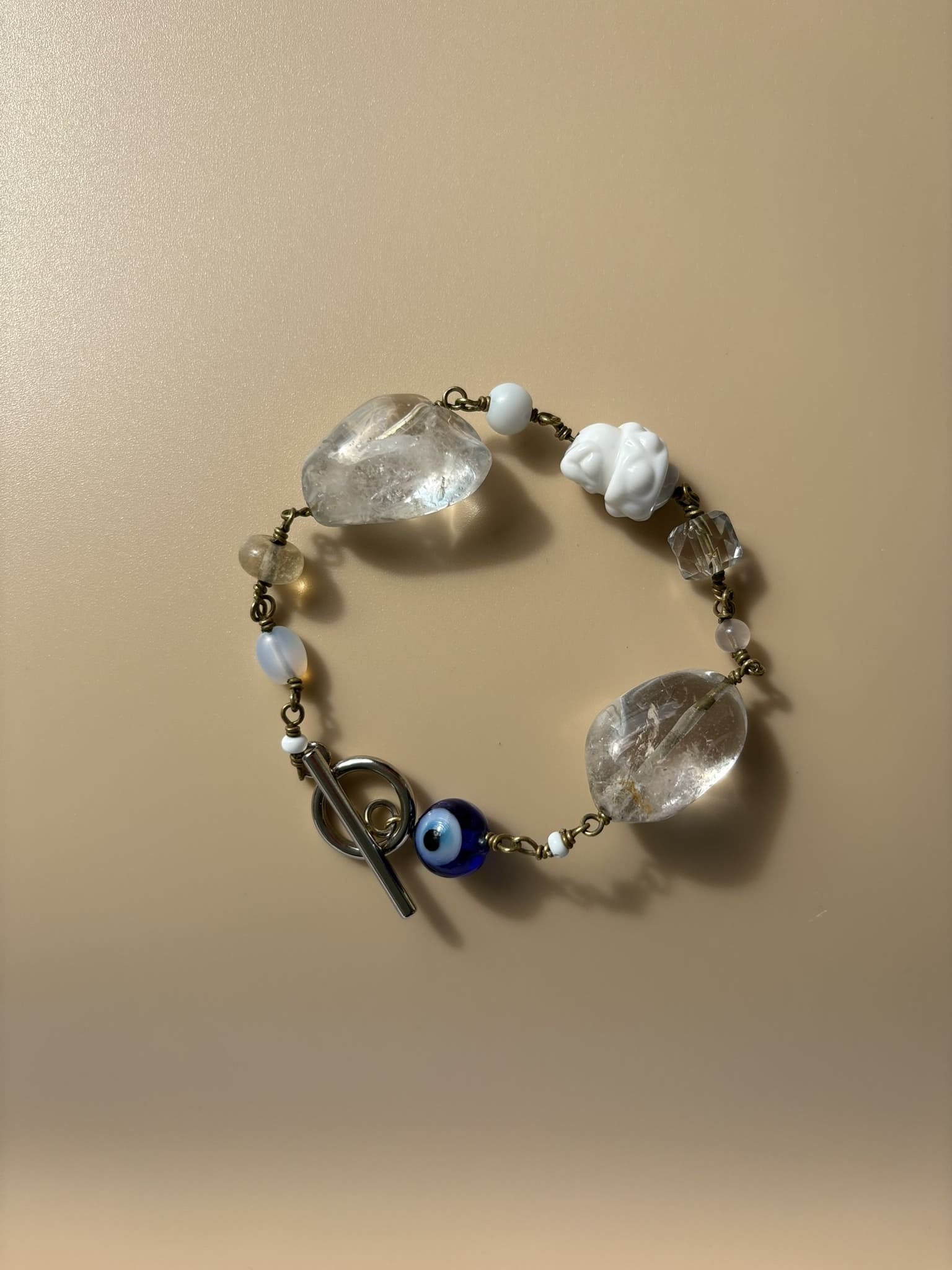 Rock crystal and pearl bracelet displayed on beige surface. Survivor-made handcrafted jewelry of strength and purity.
