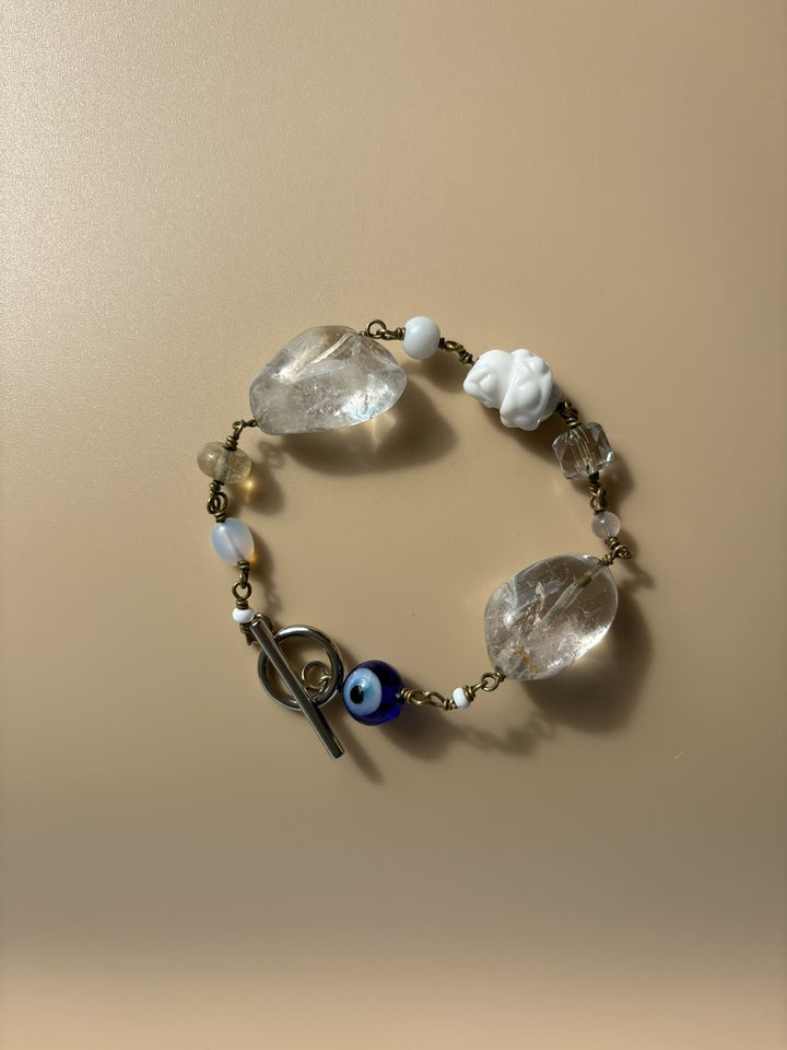 Rock crystal and pearl bracelet displayed on beige surface. Survivor-made handcrafted jewelry of strength and purity.
