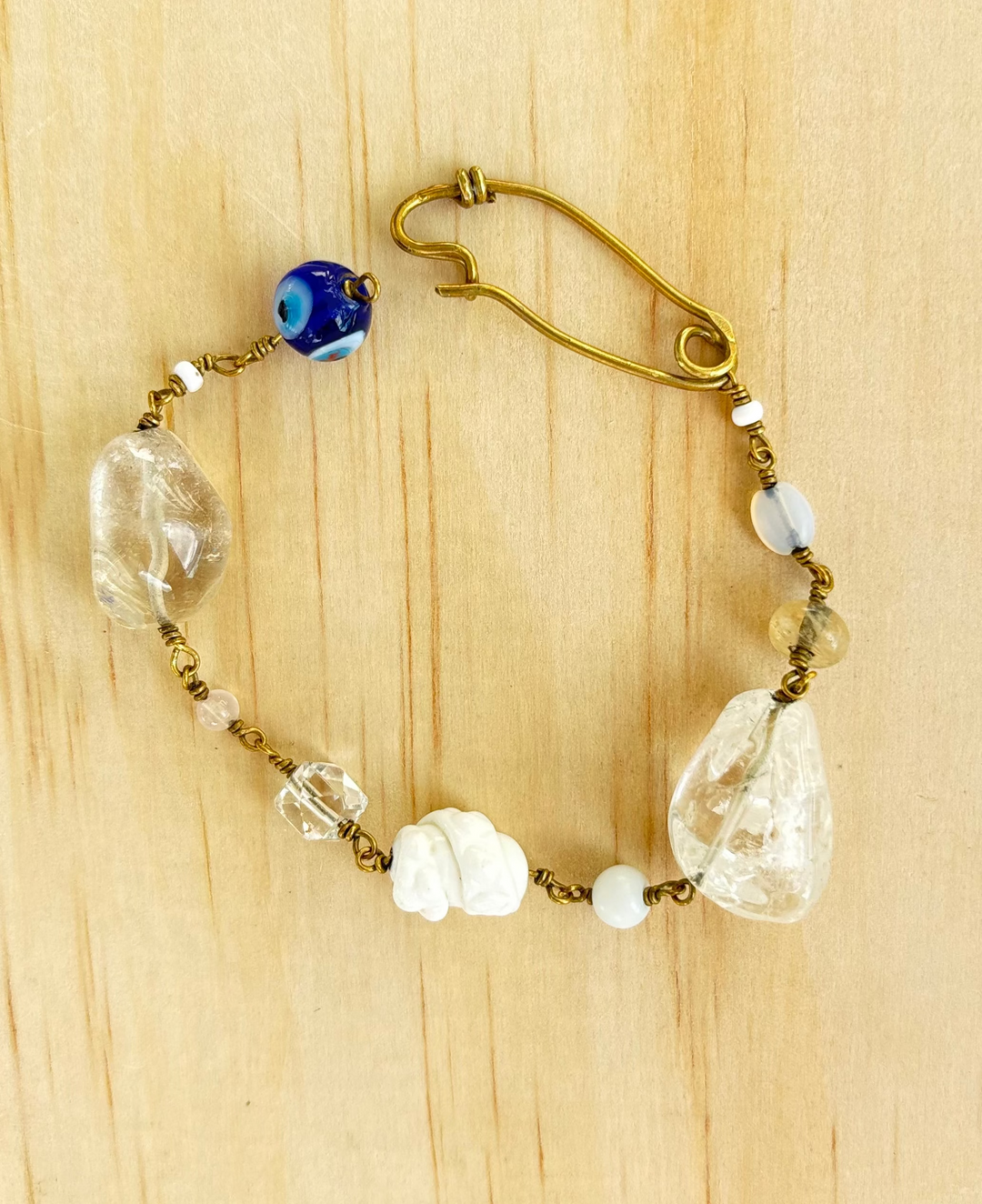 jamila rock crystal and pearl bracelet displayed on beige surface. 