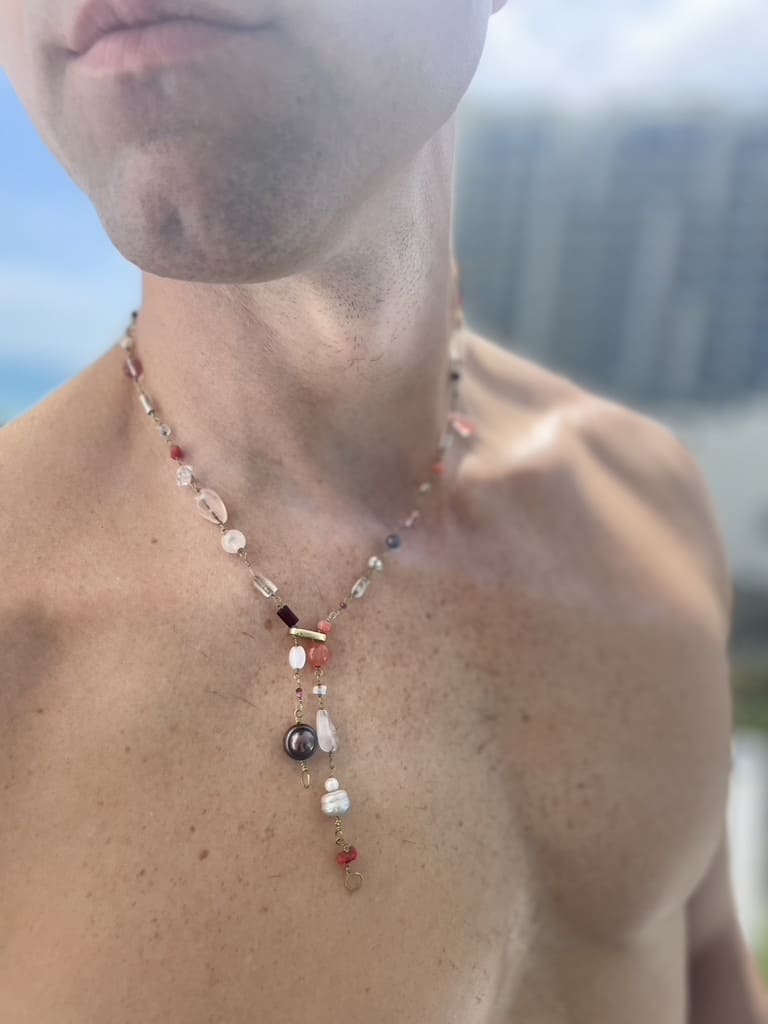 Pink gemstone necklace with rose quartz, coral, and ruby worn on model’s neck. Survivor-made ethical jewelry celebrating joy and courage.