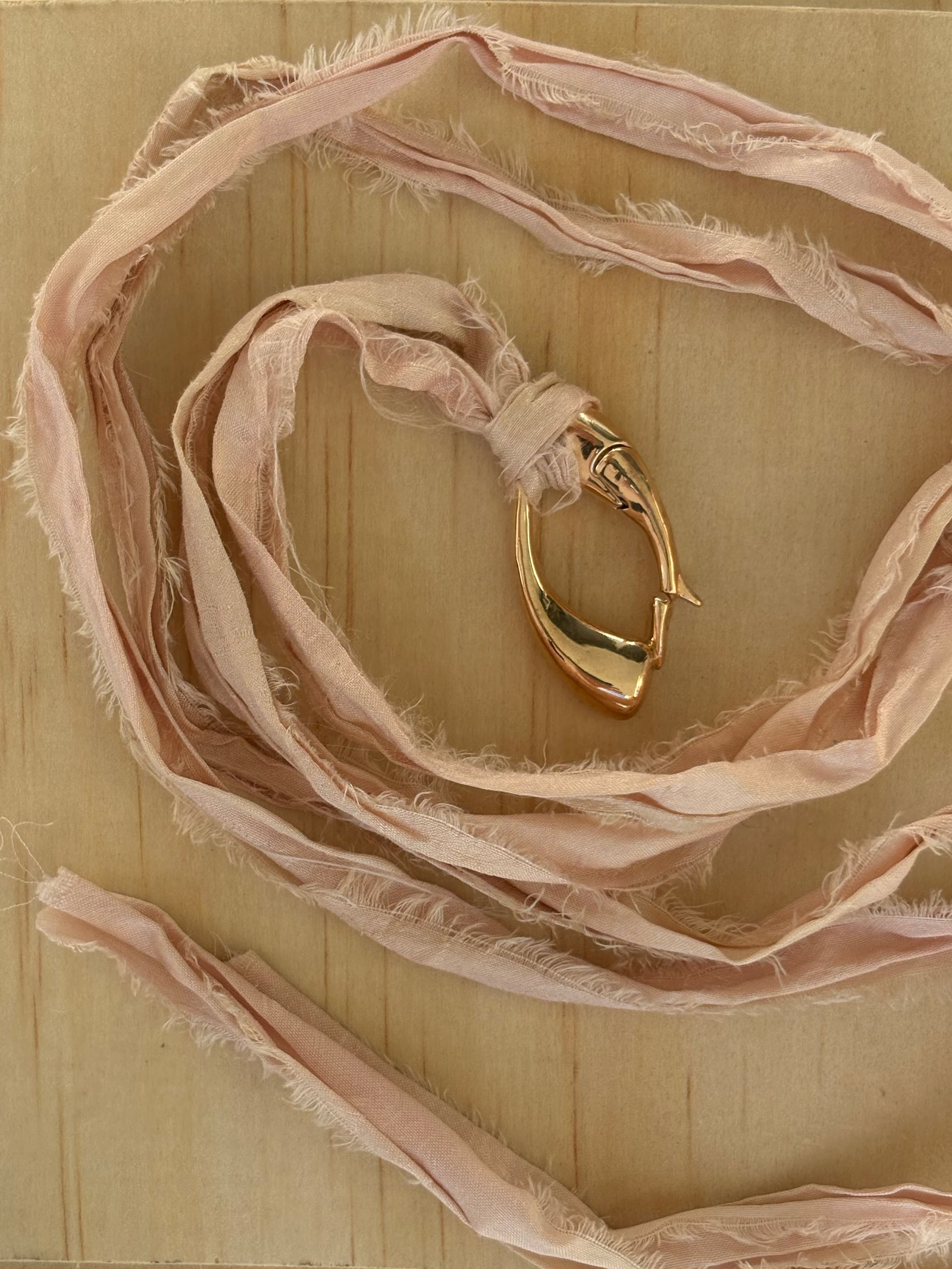 Close-up of a sculptural bronze Culebra closure onrose-colored, hand-dyed sari silk.