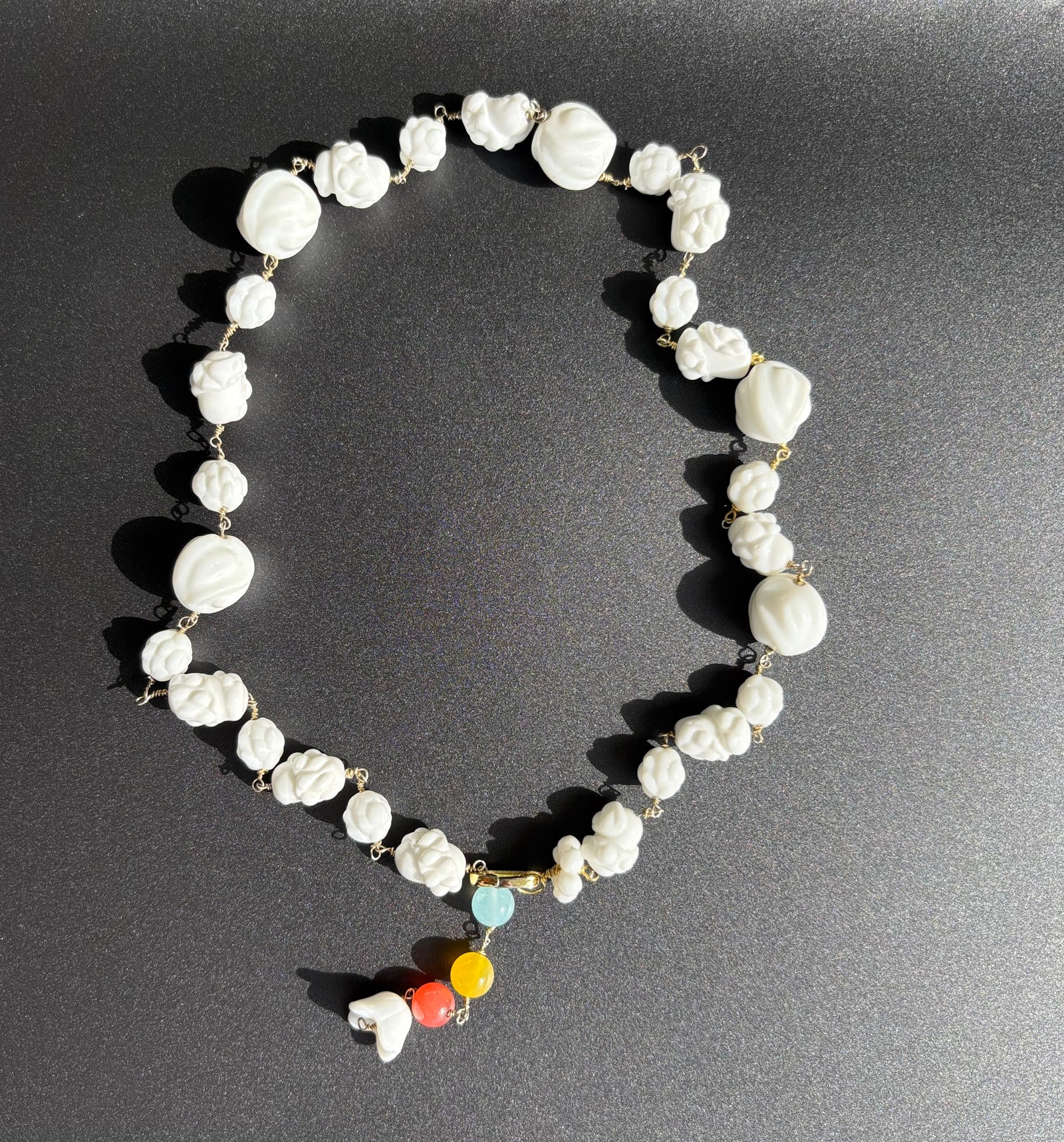 Czech porcelain and rainbow quartz necklace on black background. Survivor-made ethical jewelry of hope and resilience.