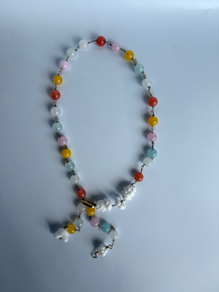 Rainbow quartz necklace displayed on grey surface. Survivor-made ethical jewelry turning grief into radiant color.