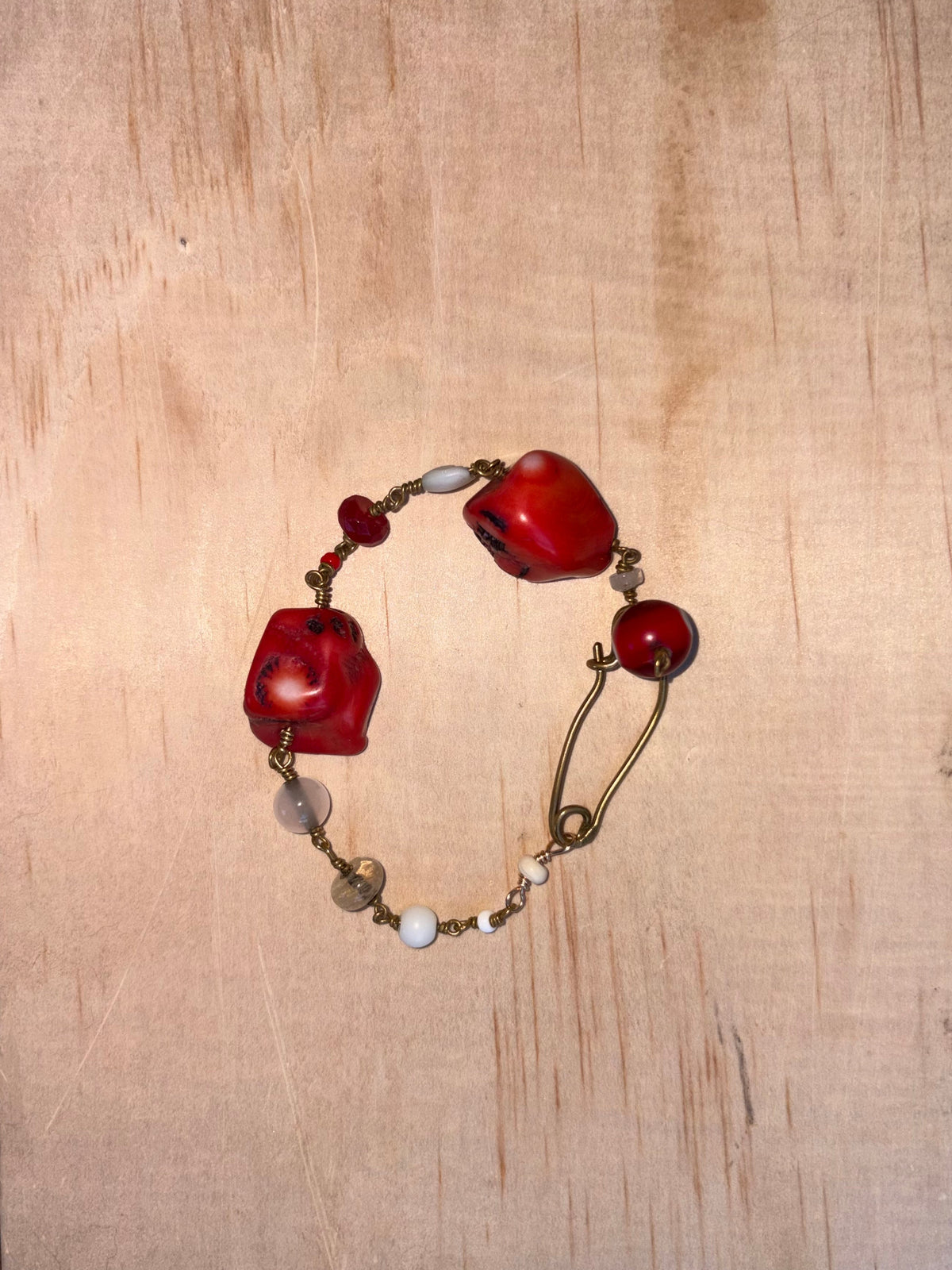 Viola Bracelet with two large red coral stones, an Evil Eye charm, pearls, and red-toned semi-precious stones with brass details.