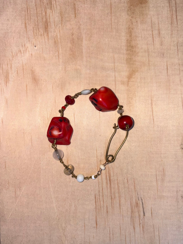 Viola Bracelet with two large red coral stones, an Evil Eye charm, pearls, and red-toned semi-precious stones with brass details.